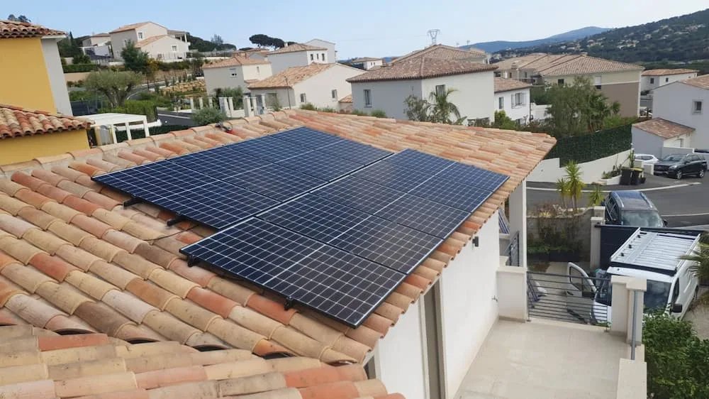 Panneaux photovoltaïques sur une toiture en tuiles au milieu d'un lotissement, vue en hauteur