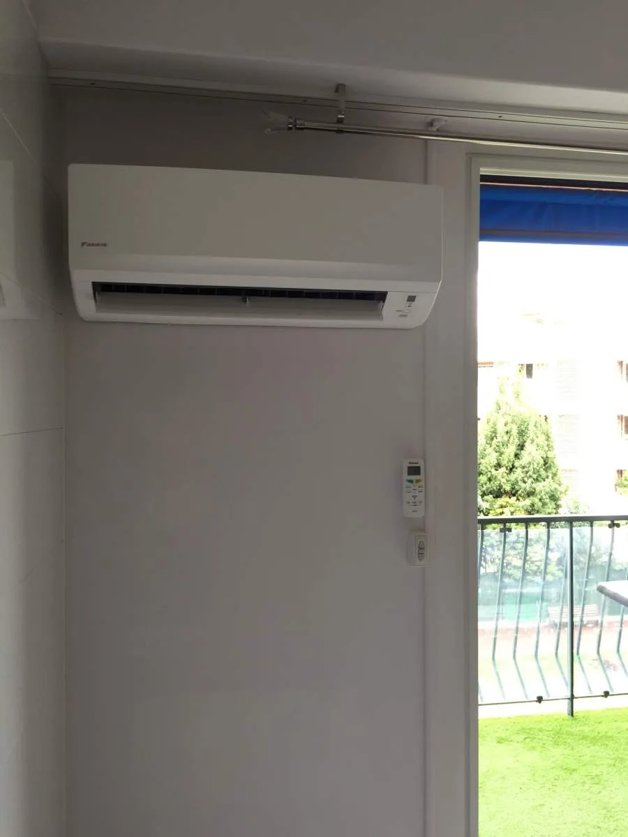 Climatiseur mural Daikin installé dans un séjour près d'une baie vitrée