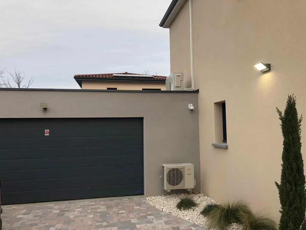 Unité extérieure de climatisation installée proprement par C.E.L Clim'Elec le long d'une maison contemporaine