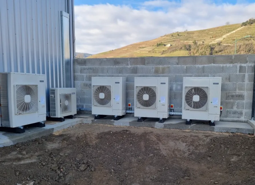 Rangée de cinq groupes extérieurs de climatisation le long d'un bâtiment